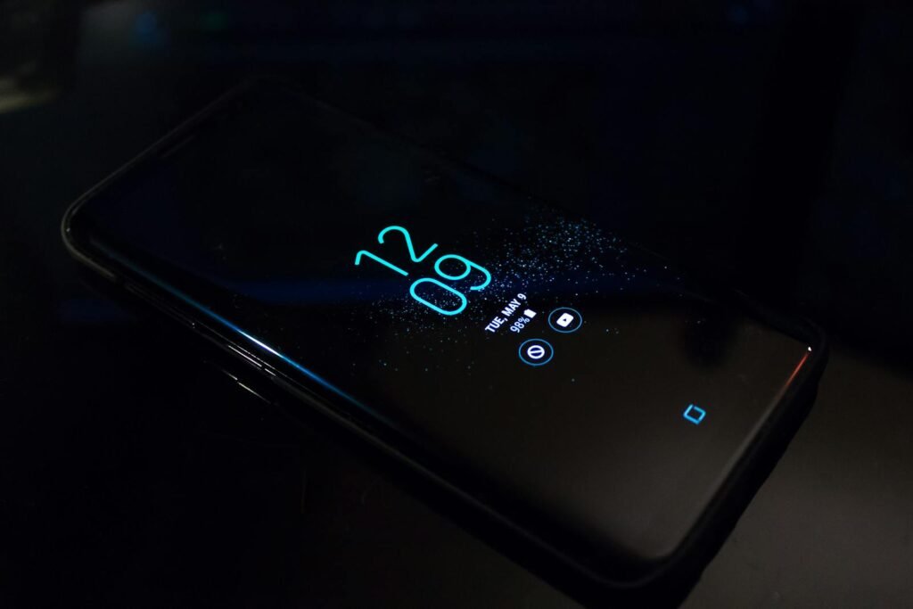 Close-up of a smartphone in the dark displaying digital clock and notifications.