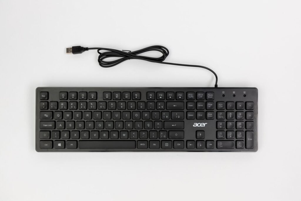 A top view of a black wired keyboard with USB connector on a white background.